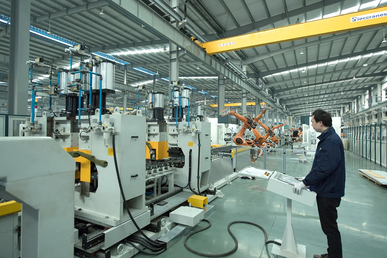 Operator overseeing automated machinery on a landing-door panel production line